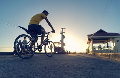 Man riding bicycle on street against clear sky