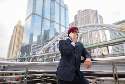 Full length of man standing on bridge against buildings in city