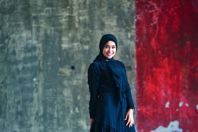 Beautiful indonesian woman wearing a black hijab against the rustic wall as a background