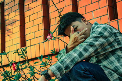 Portrait of young man showing middle finger outside building