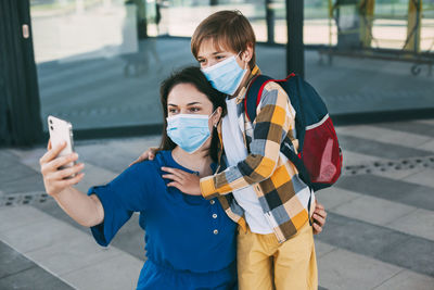 Mom and child with a masked backpack take a selfie on the phone before going to school 