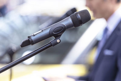 Public speaking concept. microphone in focus, blurred unrecognizable person in the background.