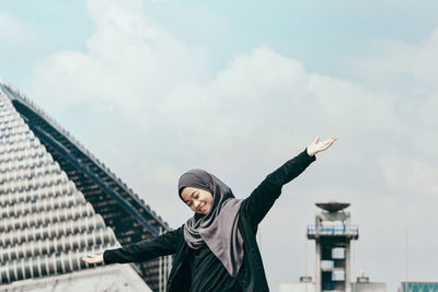 Low angle view of teenage girl standing against sky