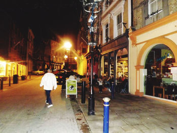 Rear view of man walking on street at night