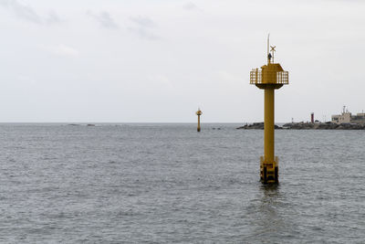 Lighthouse amidst sea and buildings against sky