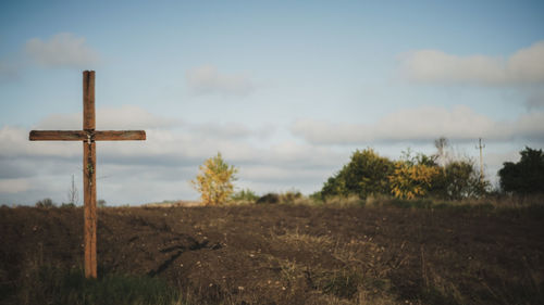 Cross on field against sky