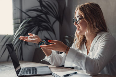 Portrait of young woman using mobile phone at office