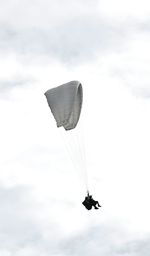 Low angle view of person paragliding against cloudy sky