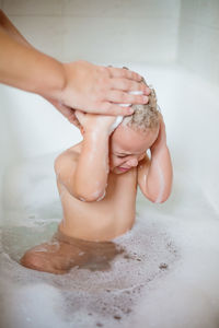 Cropped hands of parent bathing baby boy