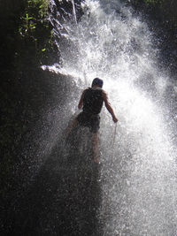 Man rappels down waterfall while canyoneering on rock