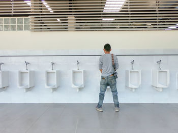 Rear view of man standing at public urinal