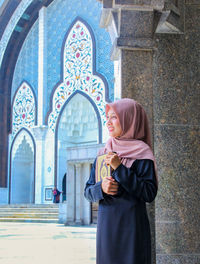 Woman holding holy book while standing in mosque