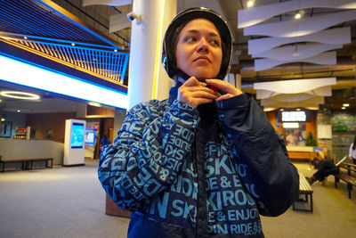 Portrait of young woman standing against building