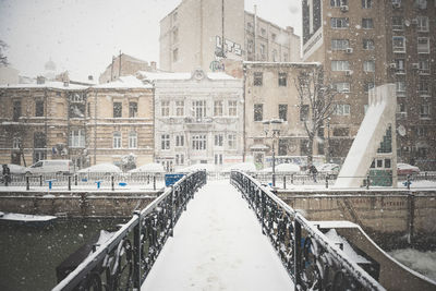 Snow covered street amidst buildings in city