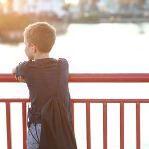 Rear view of boy looking at railing