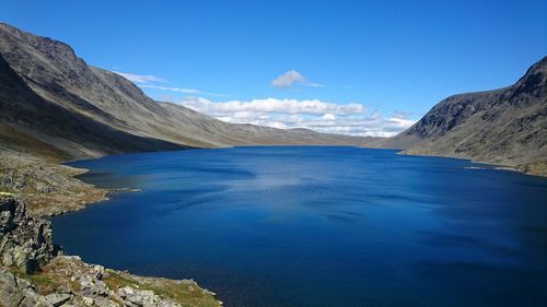 Scenic view of sea and mountains against blue sky