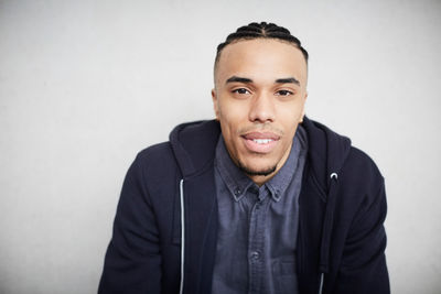 Close-up portrait of young male student sitting against wall in university