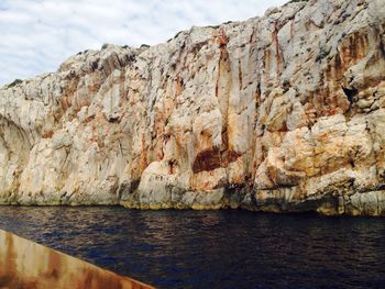 Rock formations by sea against sky