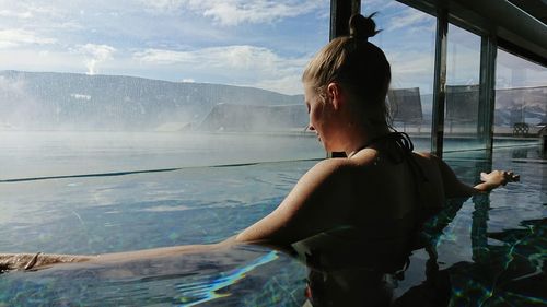Rear view of woman standing by sea against sky
