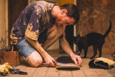 Man working with skateboard while kneeling on floor