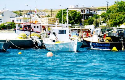 Boats moored in sea against sky in city