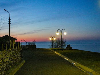 Street light by sea against sky during sunset