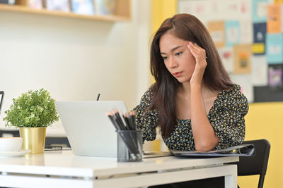 Young woman using phone while sitting on table