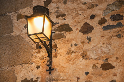 Low angle view of illuminated lantern on wall