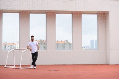 Man standing by goal post in front of windows