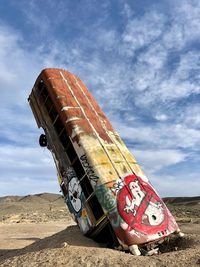 Low angle view of abandoned ship on beach against sky