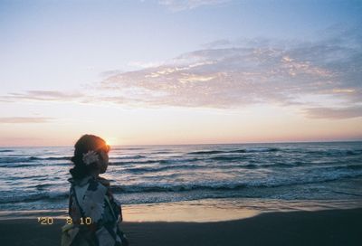 Woman on beach against sky during sunset