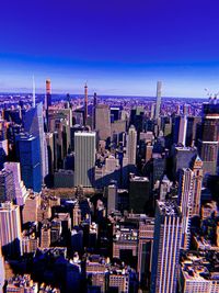 High angle view of modern buildings in city against blue sky