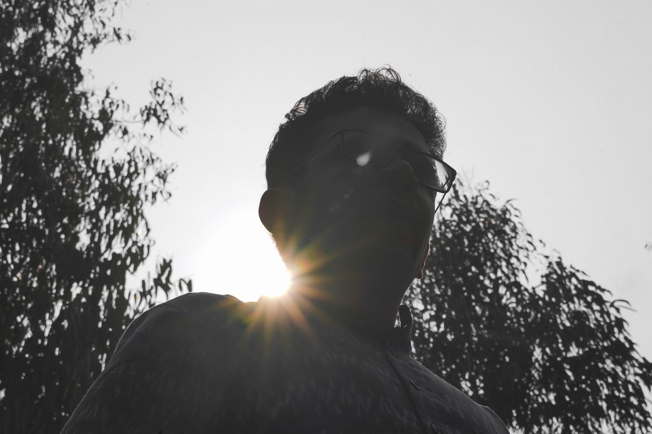 LOW ANGLE PORTRAIT OF MAN AGAINST CLEAR SKY