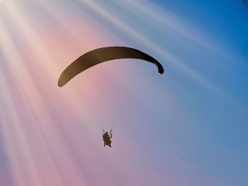 Low angle view of person paragliding against sky