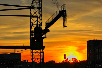 Low angle view of silhouette crane against sky during sunset