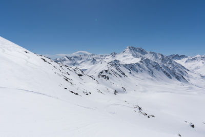 Scenic view of snowcapped mountains against clear blue sky