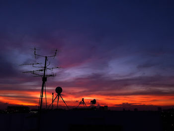 Low angle view of silhouette communications tower against sky during sunset