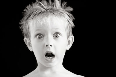 Portrait of shocked boy against black background