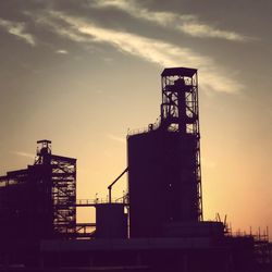 Low angle view of silhouette factory against sky during sunset