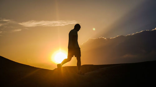 Silhouette man standing on mountain against sky during sunset