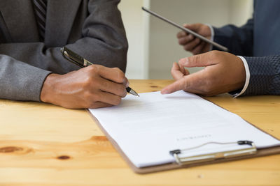 Midsection of business people discussing over document at office