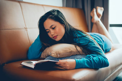 Young woman reading book at home