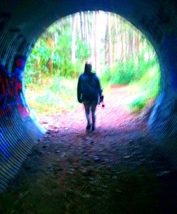 Rear view of man walking in tunnel