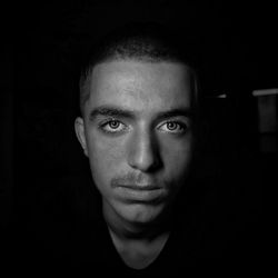 Close-up portrait of young man against black background