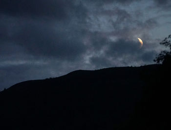Low angle view of silhouette mountains against sky at night