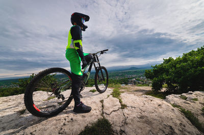 A wide angle of a young mountain bike rider in a helmet and a protective suit on his mountain bike