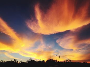 Low angle view of silhouette trees against dramatic sky