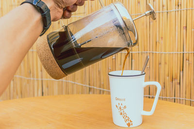 Close-up of hand holding coffee cup on table