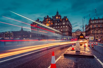 Light trails on road against buildings at night