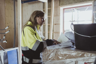 Blond female building contractor analyzing floor plan at construction site
